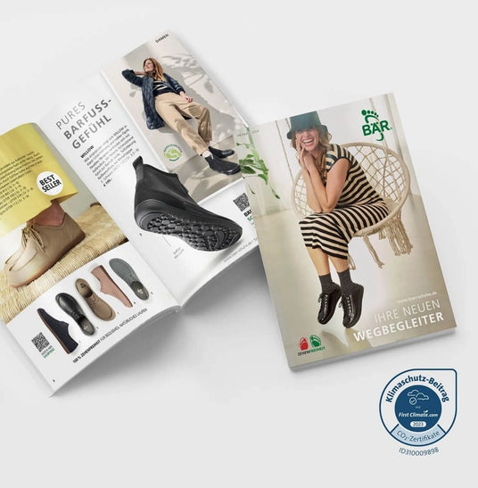 Zwei offene Modekataloge von BÄR-Schuhe, die eine Frau zeigen, die lächelnd auf einer Schaukel sitzt, und die neuesten Modelle von Barfußschuhen.
